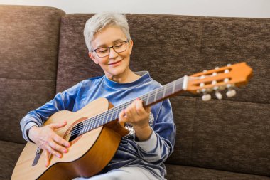 Gitar çalan şık bir yetişkin kadın.