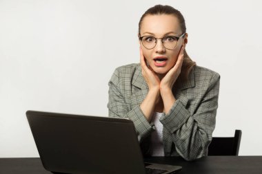 Masadaki beyaz arka planda dizüstü bilgisayarı olan güzel genç bir kadın.