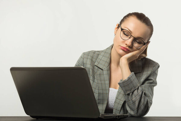 beautiful young woman at a table with a laptop on a white background
