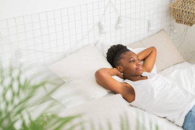  Güzel, genç, Afrikalı bir kadın beyaz bir yatakta uyuyor.