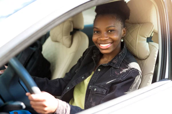 Güzel, genç bir Afrikalı kadın araba kullanıyor.