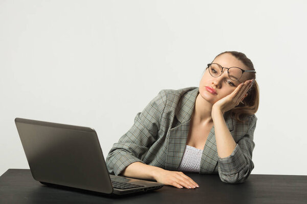 beautiful young woman at a table with a laptop on a white background