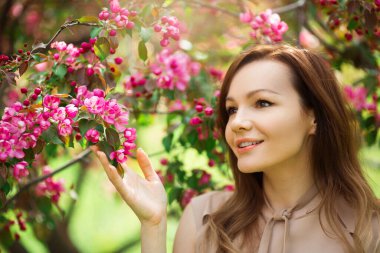 Çiçekli bir ağacın yanında makyajlı güzel bir kadının portresi.