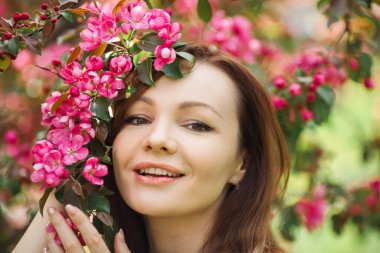 Çiçekli bir ağacın yanında makyajlı güzel bir kadının portresi.