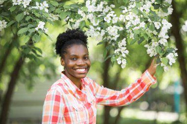  Çiçek açan bir ağacın yanında güzel bir Afrikalı kadın.