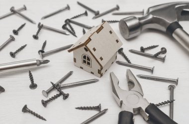 Ev inşaat kavramı arka plan. Oyuncak ev dağınık bir çivi ve vida Beyaz ahşap tahta yüzey zemin üzerine.