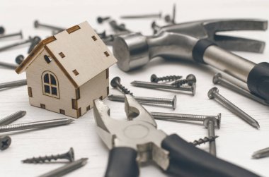 Ev inşaat kavramı arka plan. Oyuncak ev dağınık bir çivi ve vida Beyaz ahşap tahta yüzey zemin üzerine.