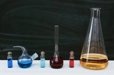 Şişeler ve şişeleri kopya alanı ile okul yazı tahtası arka plan üzerinde renkli sıvı. Eğitim kavramı. Kimyager Resepsiyon Masa.