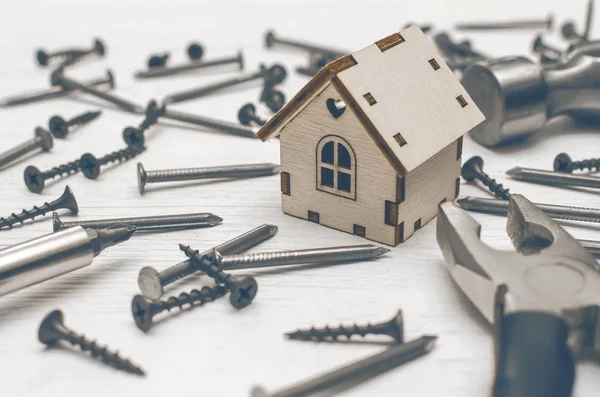 Ev inşaat kavramı arka plan. Çekiç ve çivi ve Beyaz ahşap masa kurulu kağıt oyuncak ev.