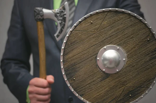 İşadamı elinde tutan bir oyuncak viking baltası silah ve kalkan. Hayat ya da Finans sigorta acentası. Para biriktirme güvenlik Aracısı.
