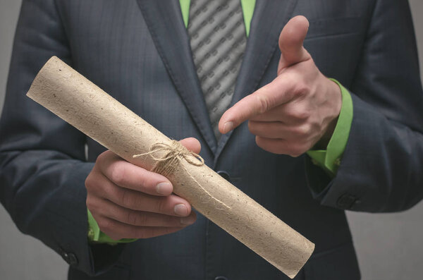 Бизнесмен держит в руках свернутый в бумагу свиток. Подписание соглашения. Заключение делового контракта. Концепция бизнес-сделки. Специальное предложение
