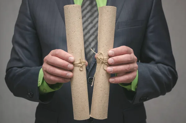 Businessman holds in hand a rolled up document scroll. Signing of an agreement. Conclusion of a business contract. Business deal concept. Special offer