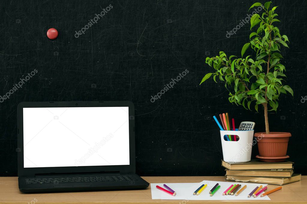 Teacher or student desk table. Education background. Education concept. Laptop with blank screen, books, copybook with pen and colour pencils on the table.