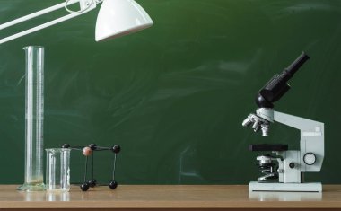 Öğretmen ya da öğrenci Danışma tablo. Eğitim arka plan. Eğitim kavramı. Yazı tahtası (yazı tahtası) arka plan üzerinde lambalı mikroskop, şişeler ve molekül modeli tablosundaki. Kimya veya biyoloji ders.