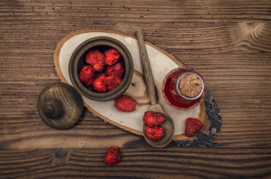 Bitkisel Tıp kavramı. Çilek ahşap kahverengi masa üzerinde kavanoz ve çilek uçucu yağda kuru. Organik maddeler.