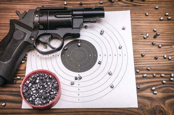 Gun pistol and paper target with scattered bullets around. Shooting practice. Shooting range background with copy space.