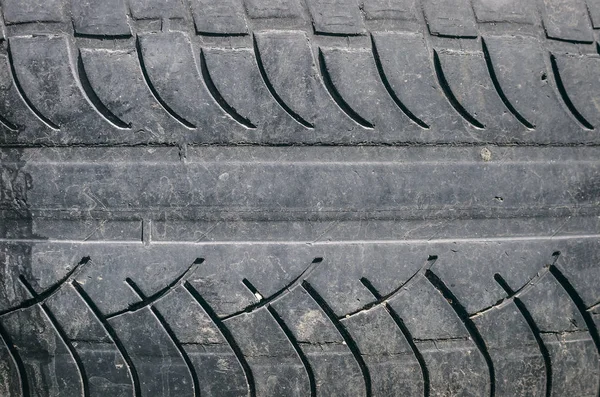 Old car tire tread texture background. Worn out protector of car tire. Used wheels close up.