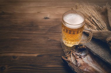 Köpük bira bir bardağa, çuval bezi kopya alanı bir yanık ahşap masa zemin üzerine sarılı balık stockfish ve çavdar kulakları kurutulmuş.