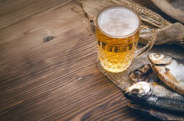 Köpük bira bir bardağa, çuval bezi kopya alanı bir yanık ahşap masa zemin üzerine sarılı balık stockfish ve çavdar kulakları kurutulmuş.