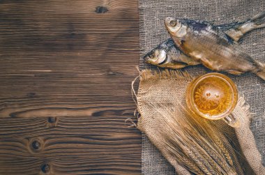 Köpük bira bir bardağa, çuval bezi kopya alanı bir yanık ahşap masa zemin üzerine sarılı balık stockfish ve çavdar kulakları kurutulmuş.