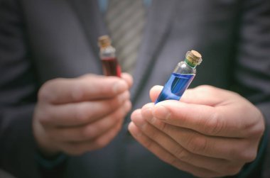 Mavi ve kırmızı hapı temel sıvı iş adam elinde. Doğru hap seçme. Steroid veya ilaç tanıtımı. Tüm hastalıkları kavramı için ilaç. Antibiyotik hap karşılaştırma.