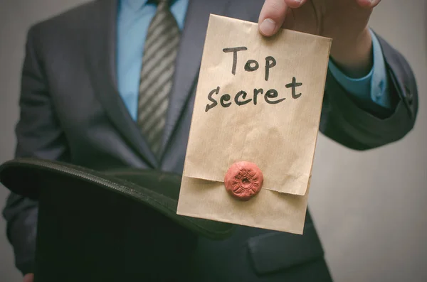 Top secret concept. Business man pick out from bowler hat a top secret documents. Confidential dossier information. Super important information.
