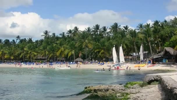 多明尼加共和国Bayahibe的Dominicus海滩 早上与太阳在一起 有小船在海上 棕榈树和游客在海滩上畅游 — 图库视频影像