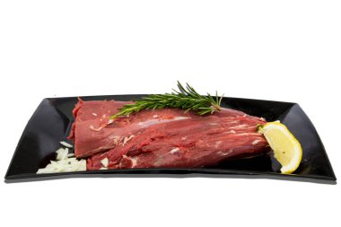 Beyaz arka planda çiğ et ve yiyecek süslemeleri olan tenha bir tabak.