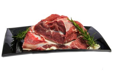 Beyaz arka planda çiğ et ve yiyecek süslemeleri olan tenha bir tabak.