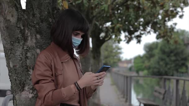 Mladá Žena Lékařskou Maskou Při Pohledu Svůj Smartphone Parku Sama — Stock video