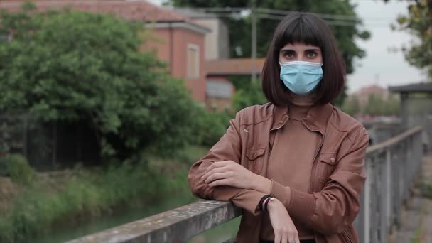 Mladá dívka s lékařskou maskou sledování v kameře v venkovní scéně 2 — Stock video