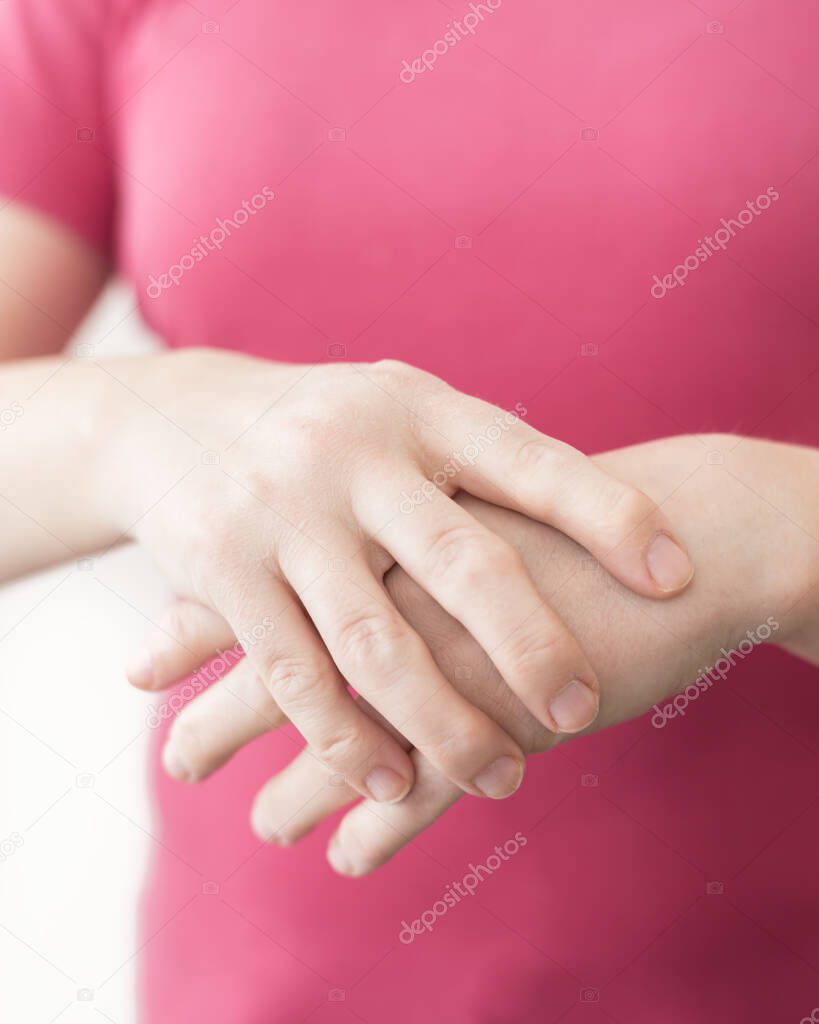 Close up young white woman suffering from pain in wrists. Health care concept with real rheumatoid arthritis hand.