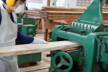 Alt ağaç makine rende ile çalışıyor. O fabrikada güvenlik ekipmanları giyiyor