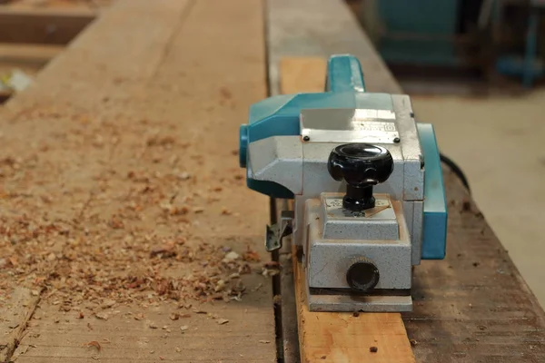 Elektrohobel mit Sägemehl auf dem Holzstück in der Schreinerei — Stockfoto