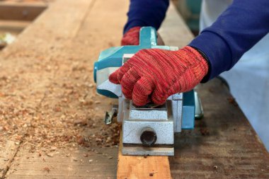 El marangoz marangozluk atölyede ahşap tahta ile elektrikli planya kullanarak