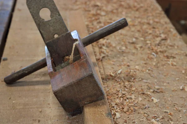 Close up van oude houten planer op een stuk hout in werkplaats — Stockfoto