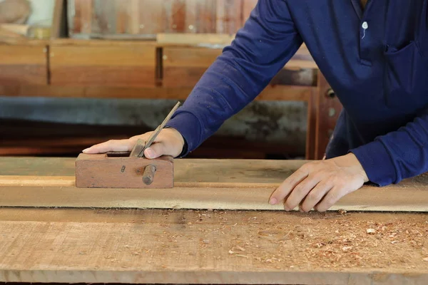 Hand eines Arbeiters, der mit einer Hobelmaschine auf einem Holzbrett arbeitet. — Stockfoto