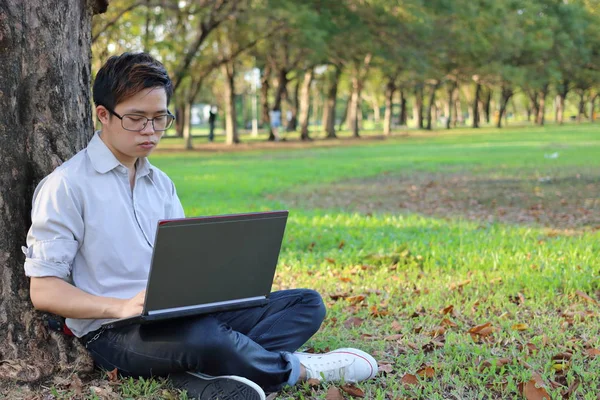 Potret seorang pengusaha muda yang serius yang mengerjakan komputer laptopnya di taman kota dengan latar belakang ruang fotokopi . — Stok Foto
