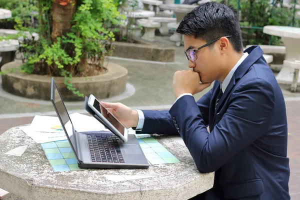 Onun tableti çalışmaları için parkta tutan yakışıklı iş adamı