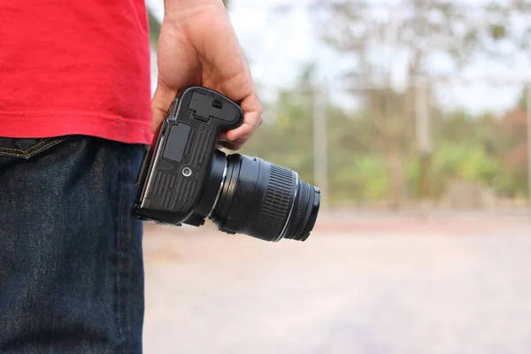 Back view of young photographer holding camera on hands with copy space background.