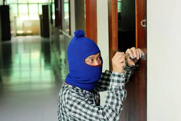 Álarcos betörő hamis kulccsal az ajtón a betörés előtt. Bűncselekmény fogalma. — Stock Fotó