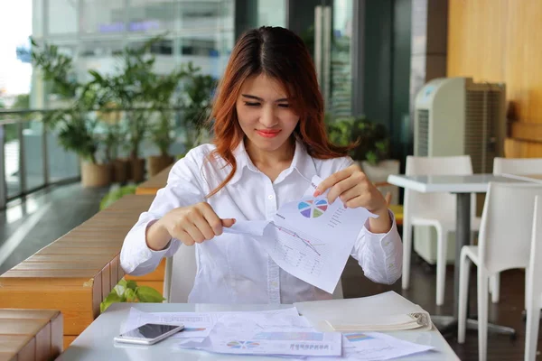 Молодая привлекательная азиатская деловая женщина разрывает бумажную работу или графики в своем офисе . — стоковое фото