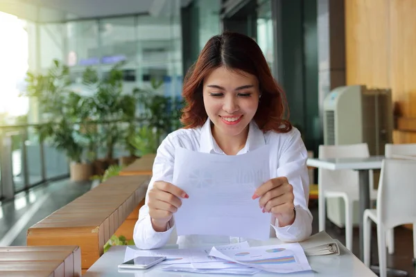 Привлекательная счастливая азиатская деловая женщина улыбается с бумагой в офисе . — стоковое фото