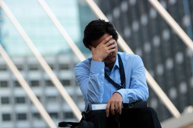 Hayal kırıklığına uğramış ve geçit şehir arka planda oturan yüz eller ile işsiz genç bir Asyalı işçi kadar kapatın.