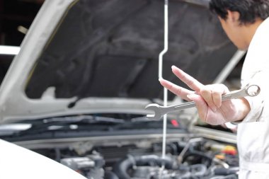 Eller yukarıya o iki parmak yükselterek mekanik adamdır profesyonel gençlerin tarih seçici odak onarım garaj arka plan açık kukuleta ile iş araba karşı mücadele gösterir.