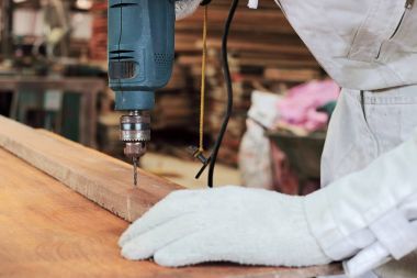 Marangoz beyaz üniforma ahşap atölyesinde çalışan elektrikli matkap kapatın.