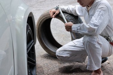 İngiliz anahtarı ve lastik tamir garaj arka plan tutan üniformalı profesyonel mekanik.