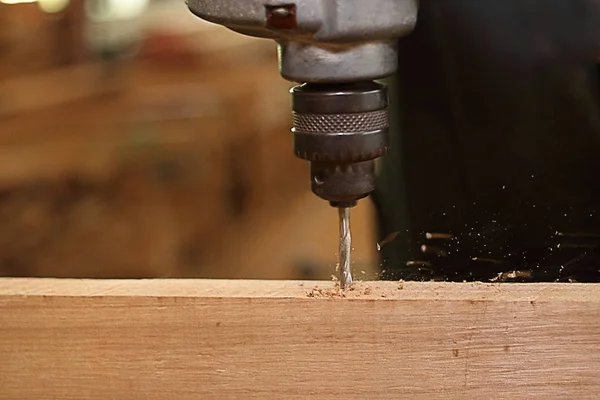 Primo piano trapano elettrico viene lavorato con tavola di legno da parte del lavoratore. Focus selettivo e bassa profondità di campo . — Foto Stock