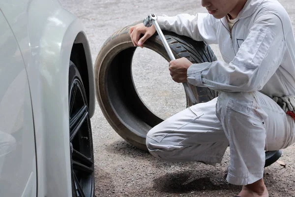 İngiliz anahtarı ve lastik tamir garaj arka plan tutan üniformalı profesyonel mekanik.