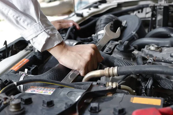 Hände des Mechanikers mit Schraubenschlüssel reparieren Motor des Autos unter der Motorhaube. — Stockfoto